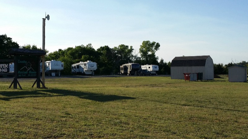 Park entrance sign with several RVs parked in a row and the on-site storage building